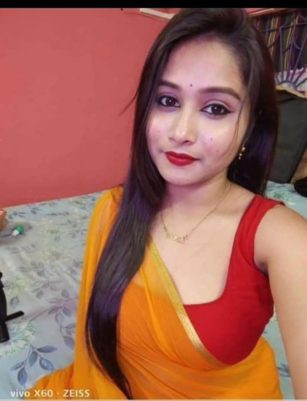 Young woman with long dark hair wearing a yellow saree, red blouse, and red lipstick.